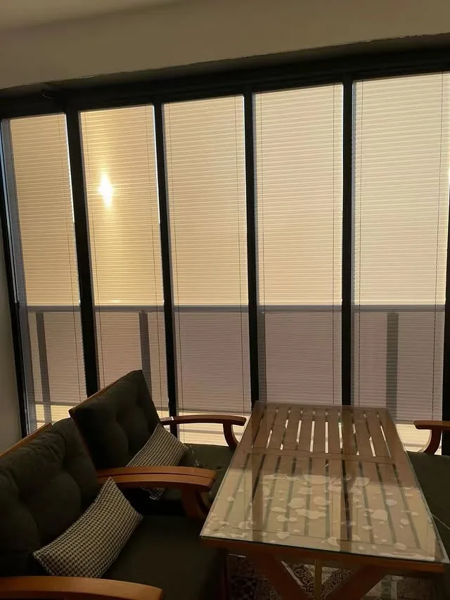 Balkon camlarına uygulanmış açık renk plise perde sistemi
